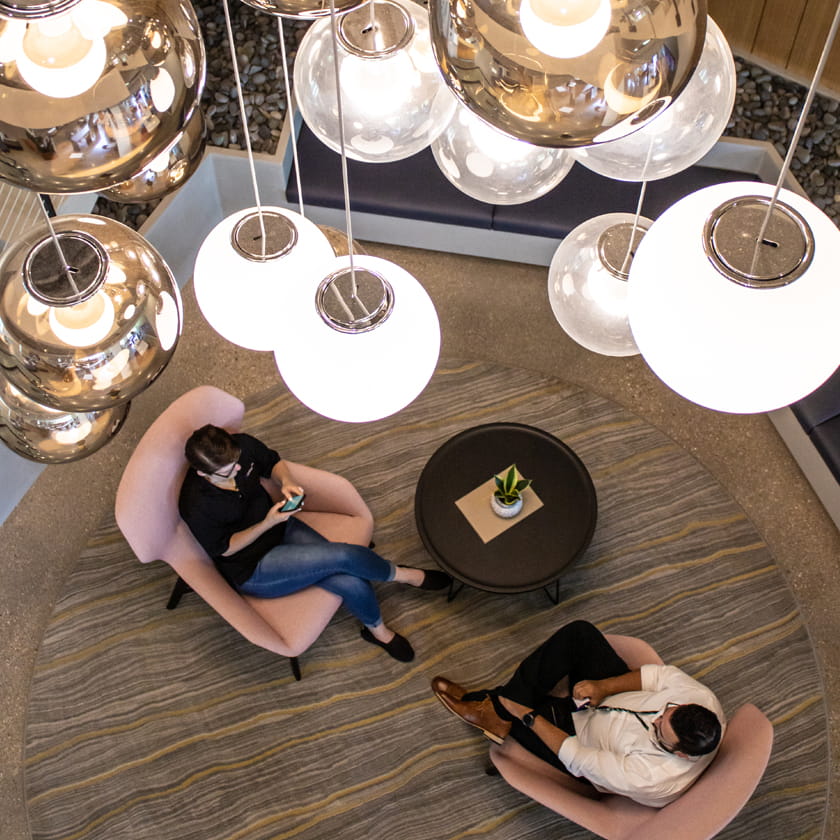 Colleagues gathering in chairs under light fixture