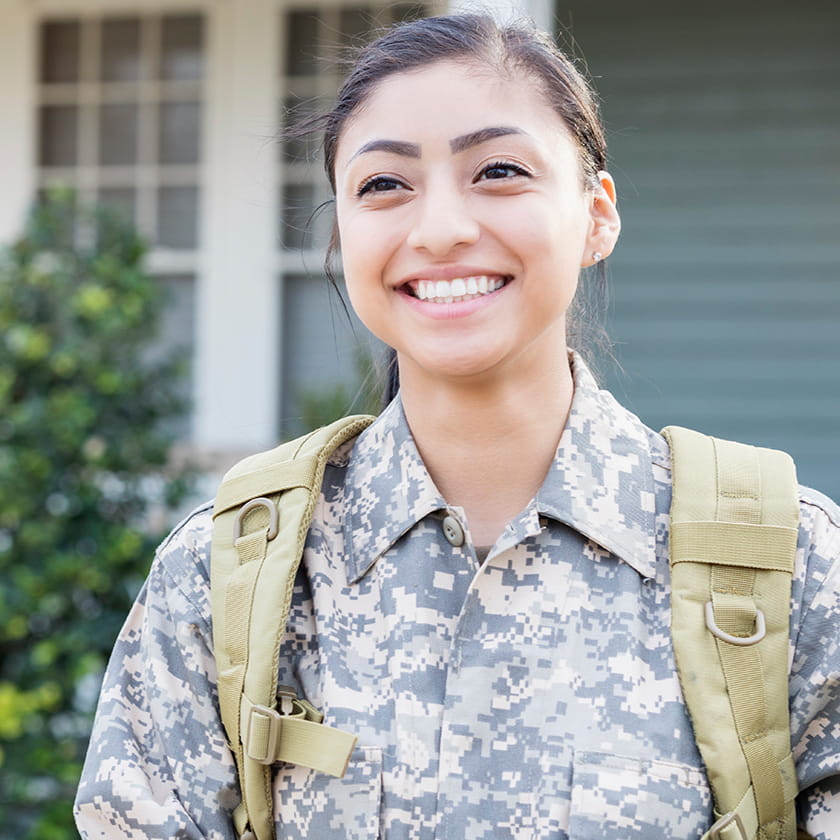 Smiling soldier standing in front of her home