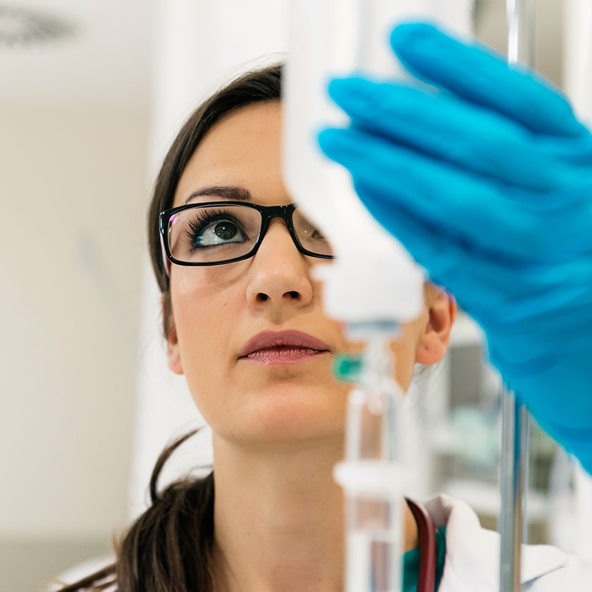 Medical professional measuring pharmaceuticals in an IV bottle