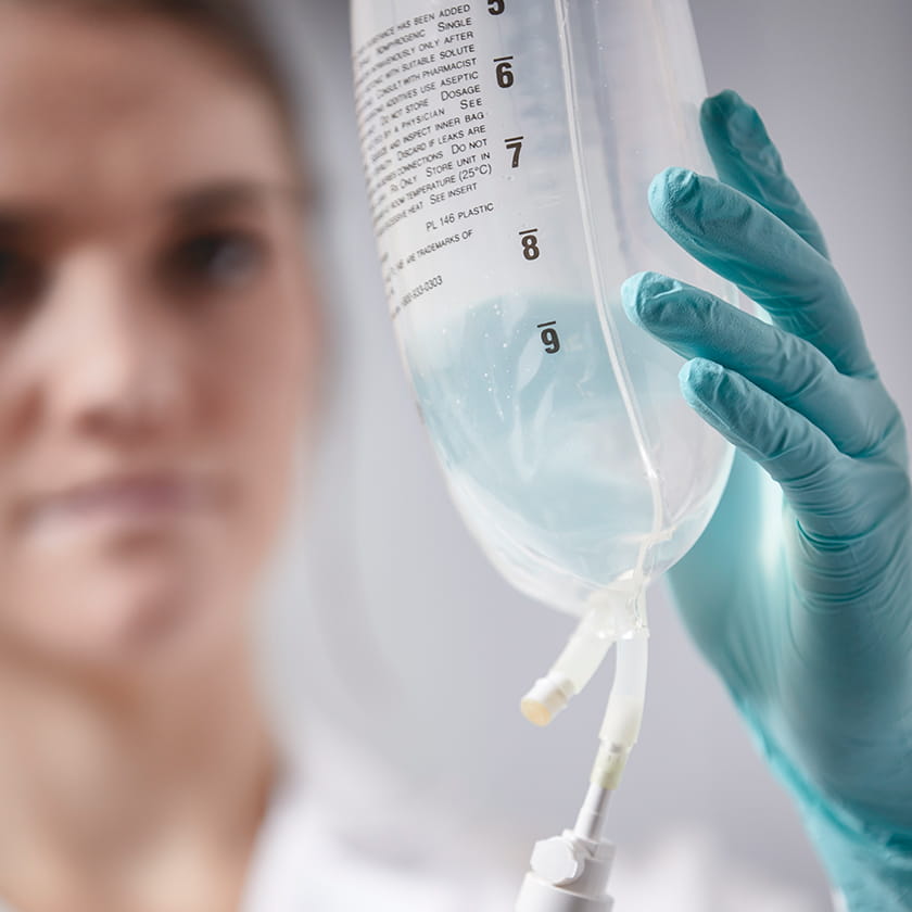 A bag of IV medication being handled by a medical professional