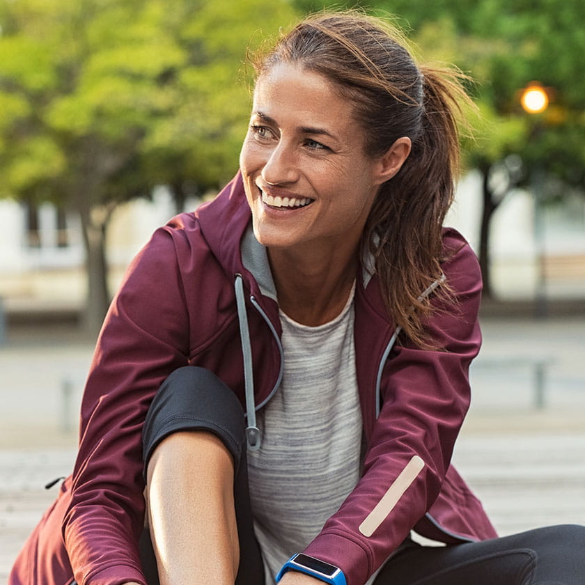 Smiling woman in workout clothes tying her shoe